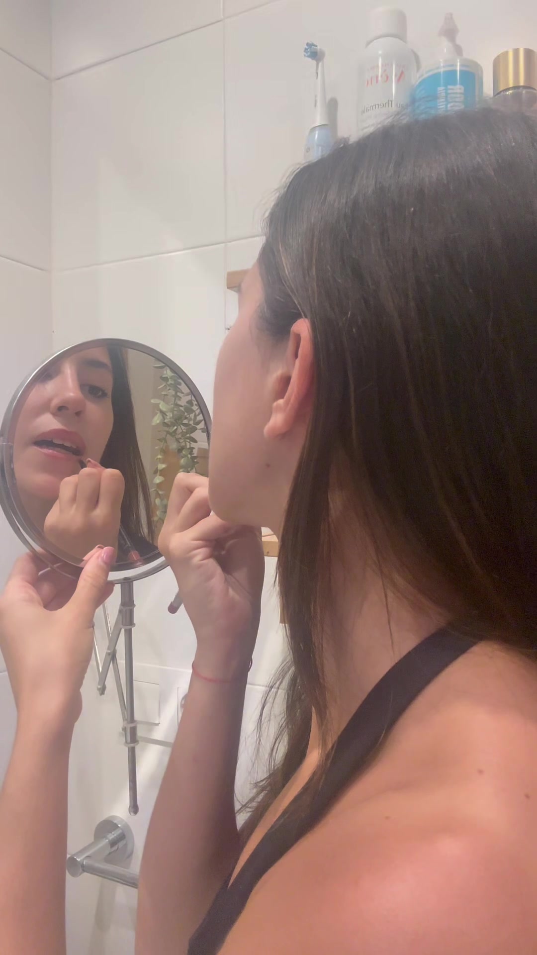 Woman applies lipstick, smiles happily